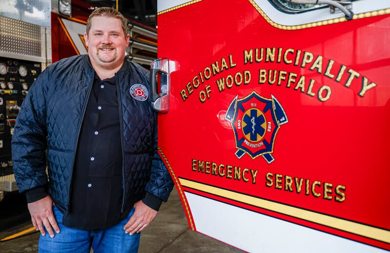 Firefighter Evan Crawford stands beside a fire truck 10 years after a wildfire in Fort McMurray, Alta., Tuesday, April 14, 2026.THE CANADIAN PRESS/Jeff McIntosh