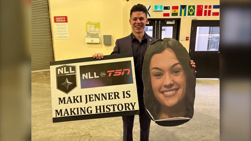 A man in a suit holds a sign that reads: "Maki Jenner is making history" with a giant photo of a woman's head.