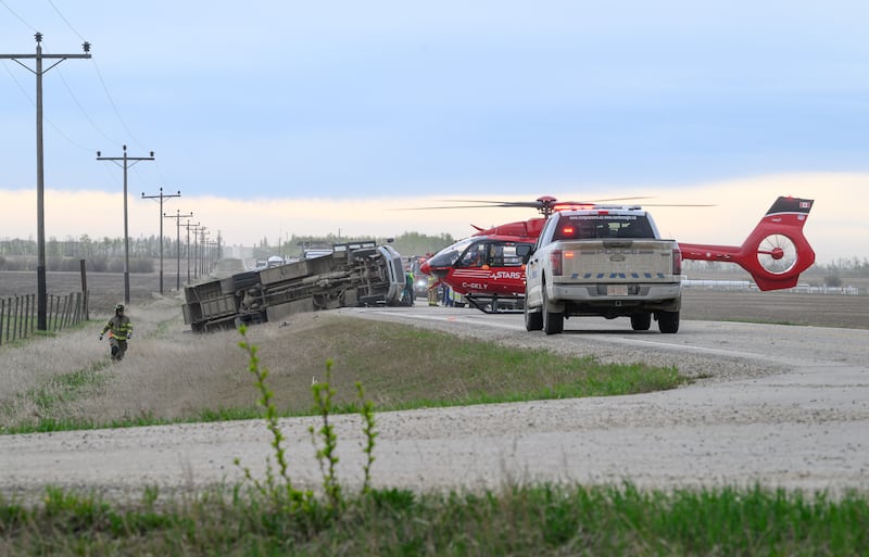 A STARS medical helicopter and a police truck are shown on Highway 672 near Beaverlodge, Alta., west of Grande Prairie, Alta., after a bus rollover resulted in several passengers being taken to hospital on Wednesday, May 13, 2026. THE CANADIAN PRESS/William Vavrek