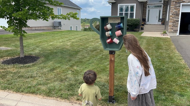 Two people look at coffee mugs outside.