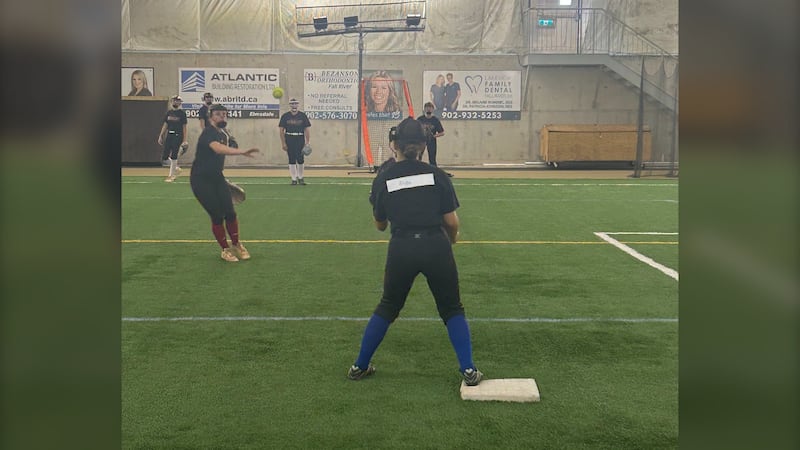 Young women play softball indoors.