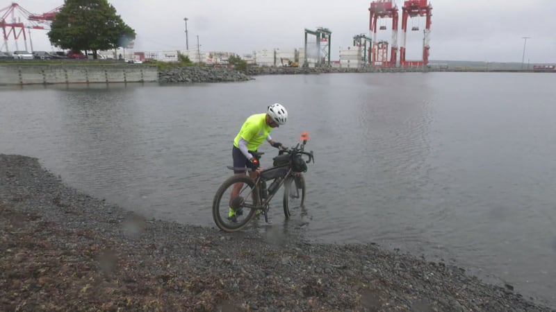 Rich Eyram dips his bike into the Atlantic Ocean in Halifax on Saturday. (CTV/Jesse Thomas)