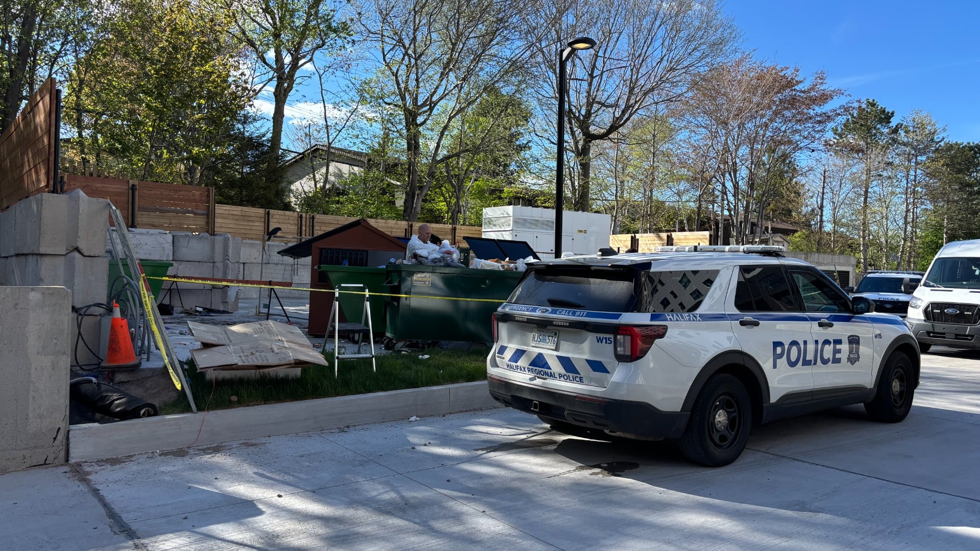 A police car in pictured next to a dumpster with police tape.