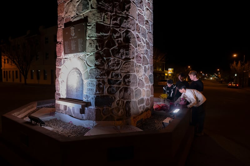 A group of young men pay their respects to the victims of a grass fire that killed four soldiers at CFB Wainwright, at the Memorial Clock Tower on Main Street in Wainwright, Alta., on Sunday, Oct. 18, 2026. THE CANADIAN PRESS/John Ulan