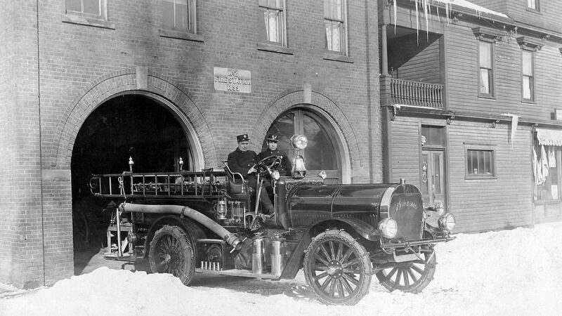 An old fire truck is pictured in a black and white photo.