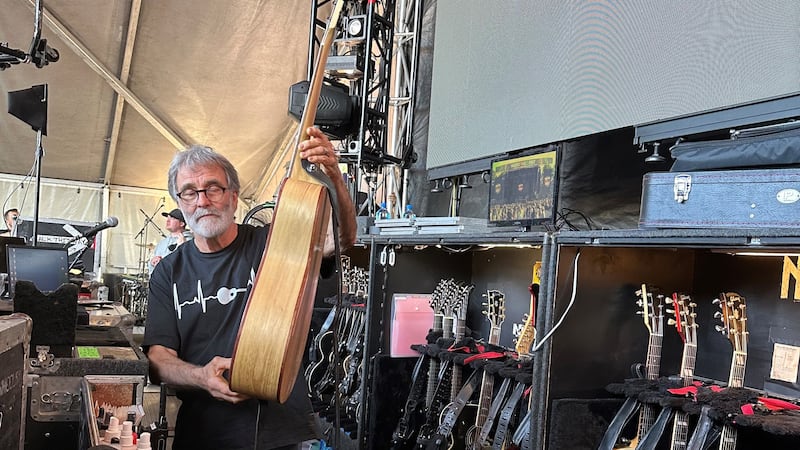Arnold London holds up a guitar.