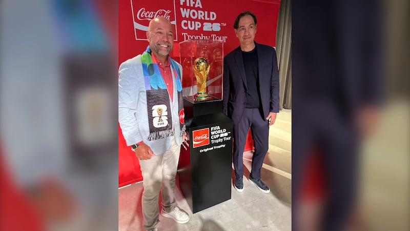 Two men pose with the FIFA World Cup Trophy.