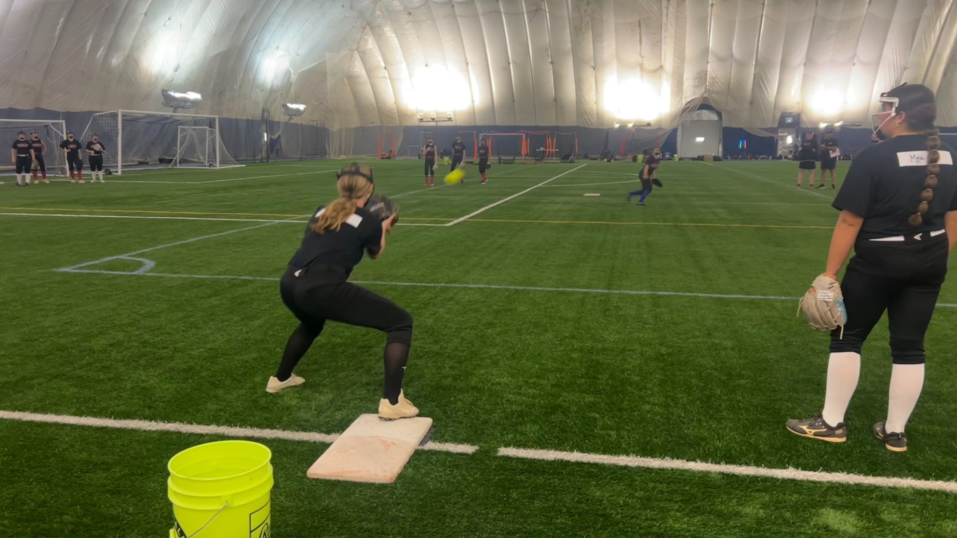 Young women play softball indoors.
