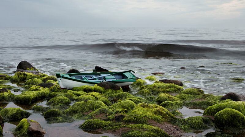 A model boat on a shore.