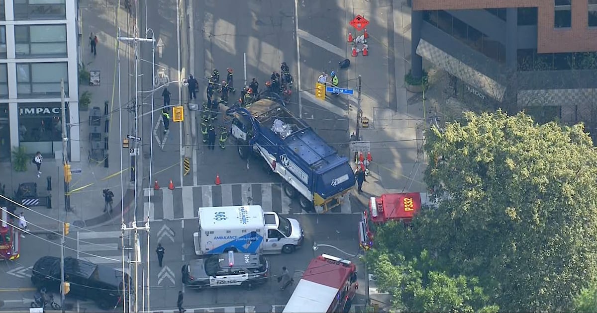 Pedestrian pinned by garbage truck in downtown Toronto