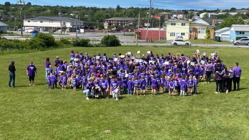 A large group of people wearing purple shirts pose for a photo.