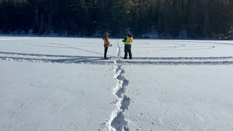 Two men are pictured standing on a lake covered in snow.