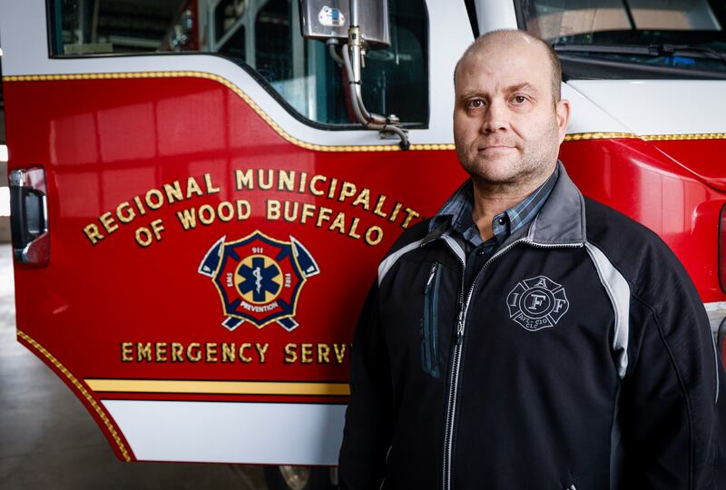 Firefighter Ryan Pitchers stands beside a fire truck 10 years after a wildfire in Fort McMurray, Alta., Tuesday, April 14, 2026.THE CANADIAN PRESS/Jeff McIntosh