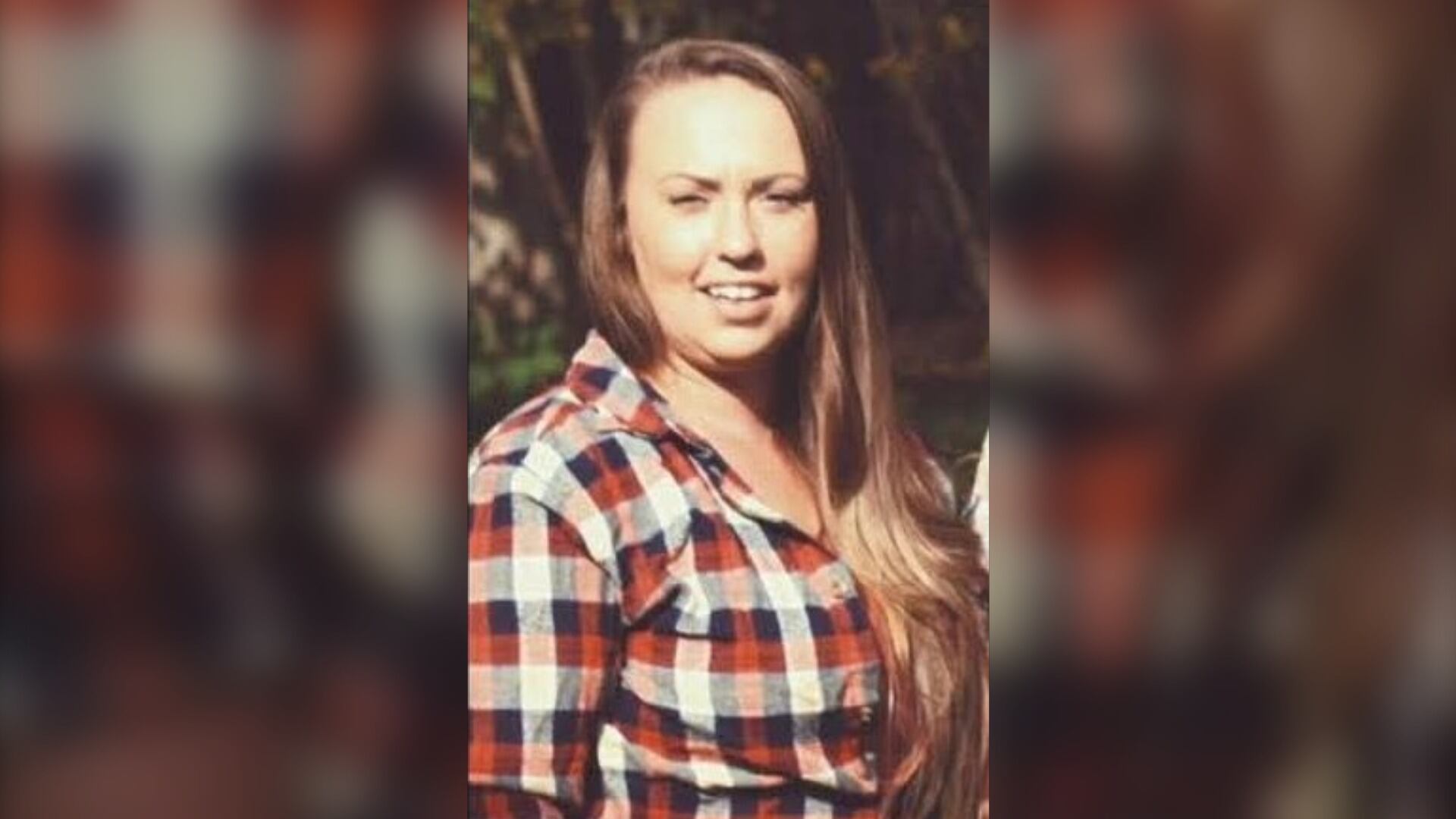 A woman with long light brown hair is pictured wearing a red, white and blue plaid shirt.