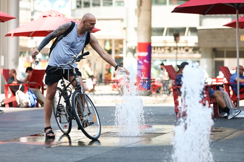 A man cools off in a fountain at Sankofa Square in downtown Toronto amid a heat wave on July 14, 2026. (Cole Burston / The Canadian Press)