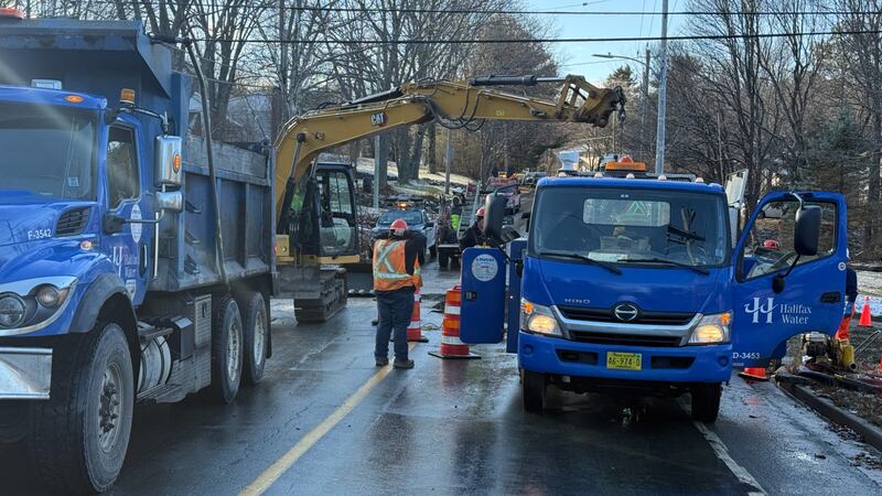 Blue construction trucks are pictured with an excavator in the background.