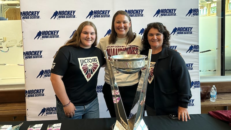 Three women pose together with a trophy for a photo.