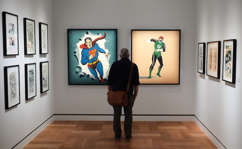 A visitor looks at Mel Ramos' oil paintings "Man of Steel," left, and "The Green Lantern" during a preview of the Lucas Museum of Narrative Art in Los Angeles on Aug. 31, 2026. (Chris Pizzello / AP Photo)