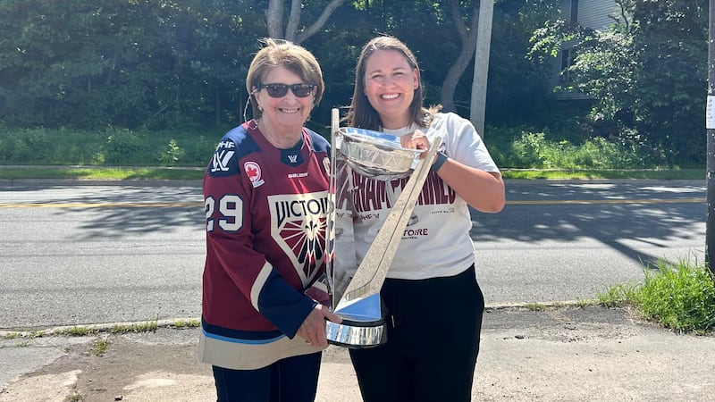 Two women hold a trophy and pose for a photo.