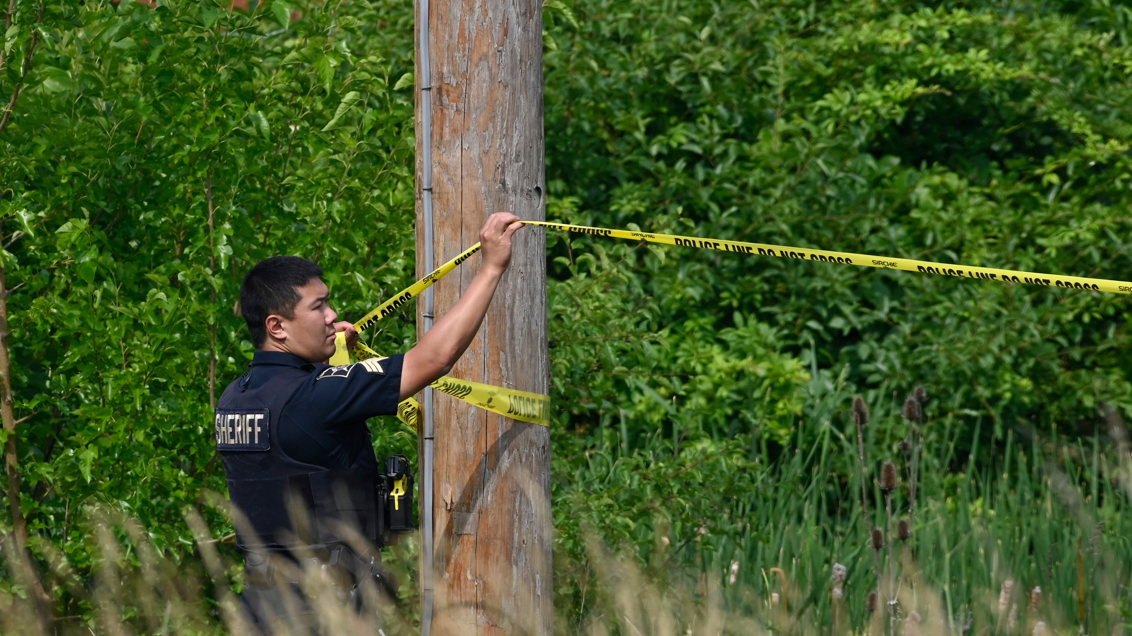 A police officer hangs caution tape at the scene of an overnight mass shooting at a strip mall in Willowbrook, Ill., on June 18, 2023. (Matt Marton / AP Photo)