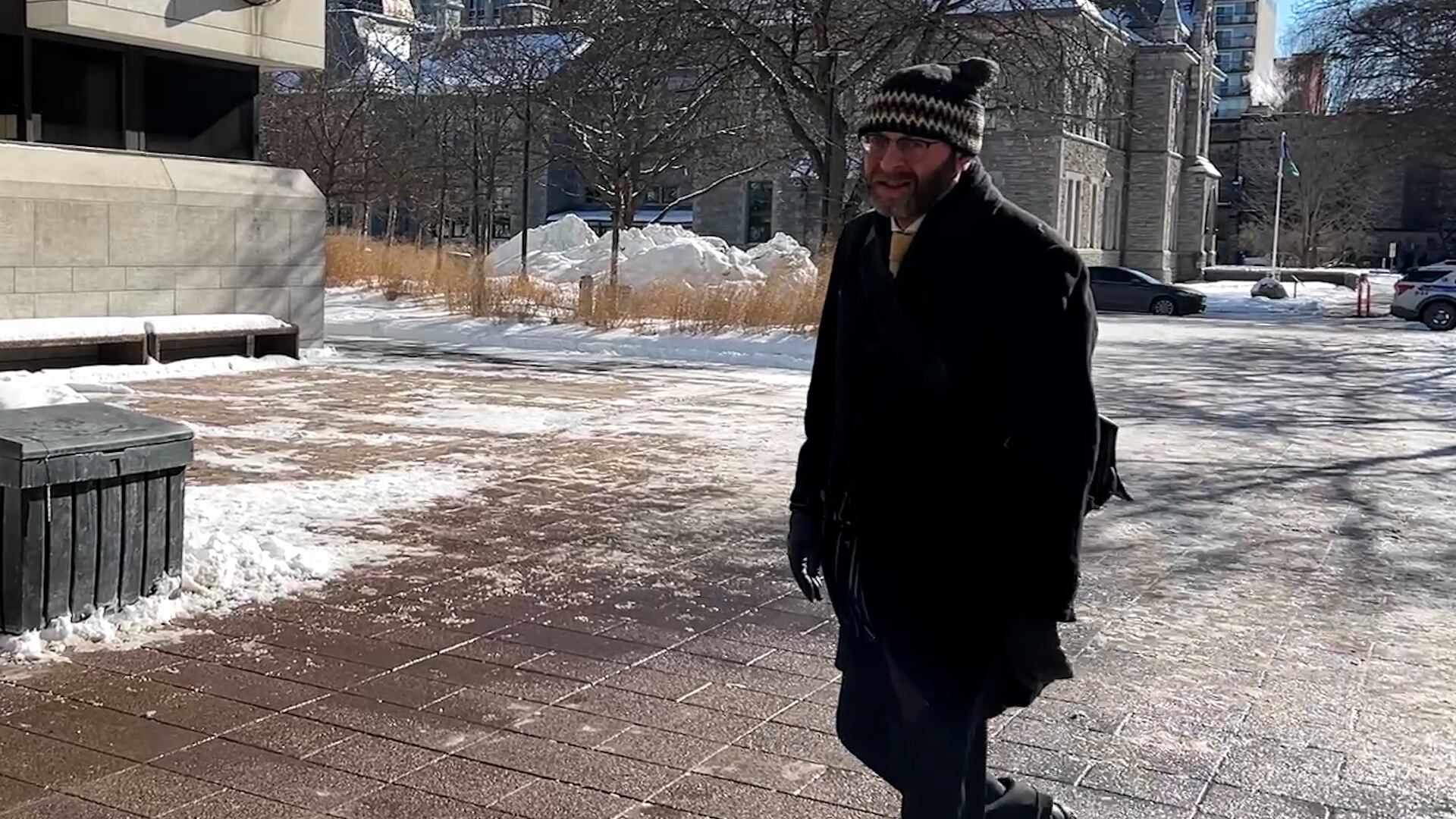 A bearded man wearing a tuque and a winter coat walks toward the Ottawa courthouse.