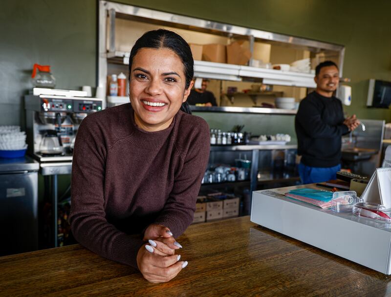 Sarah Thapa, left, behind the counter of her café 10 years after a wildfire in Fort McMurray, Alta., Wednesday, April 15, 2026.THE CANADIAN PRESS/Jeff McIntosh